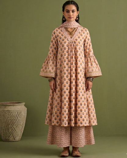 Woman wearing a patterned outfit standing against a green background